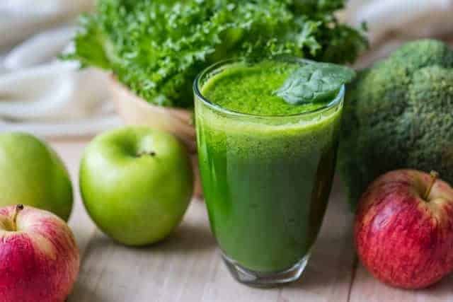 Vegetable green smoothie in a glass and apples