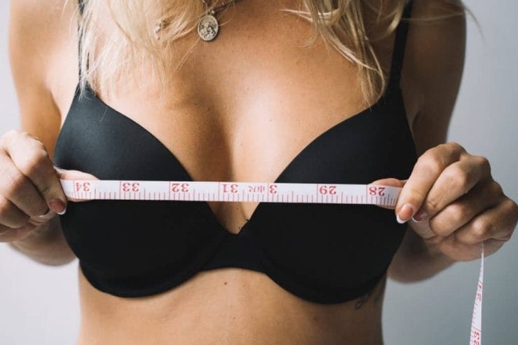 woman measures her breasts with a centimeter
