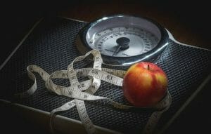 A measuring cup and an apple lying on a room scale