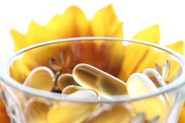 Pills in a glass, yellow flower in the background