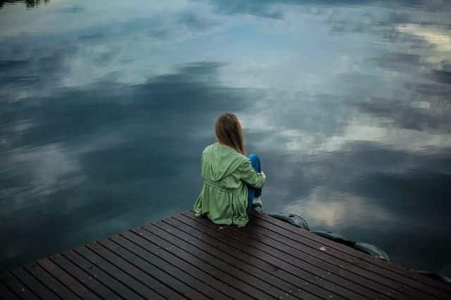  a woman sits on the edge of a pier and looks into the water