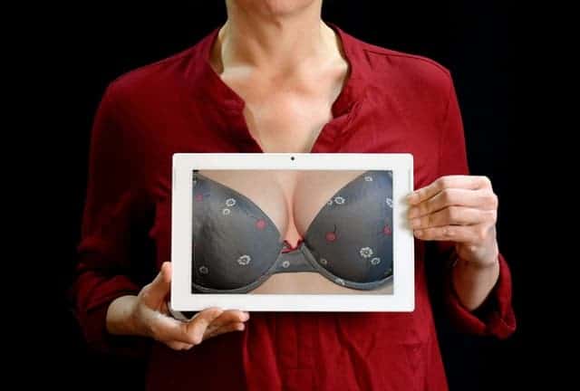 a woman holds a photo of her breasts in a push up bra