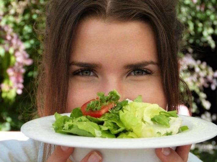 a woman holds a plate of salad