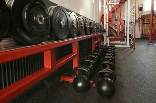 weights placed on a shelf and dumbbells on the gym floor