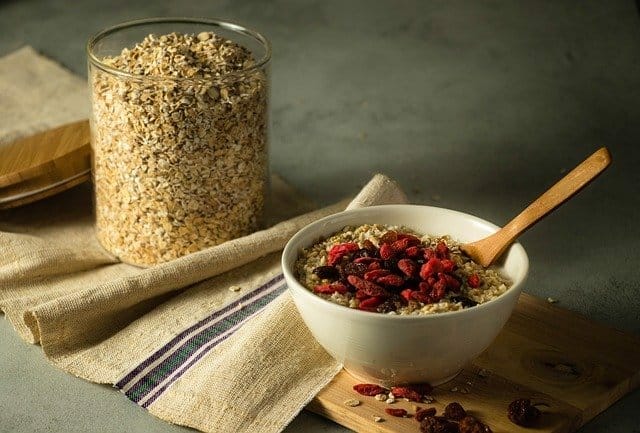 A jar with oatmeal, next to it a bowl with oatmeal