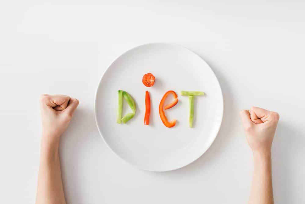 Clenched fists, a plate, a few pieces of vegetables on the plate
