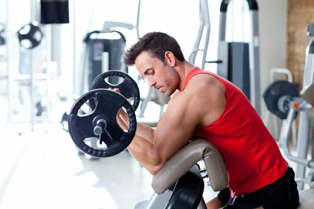 A man is exercising with a barbell at the gym.