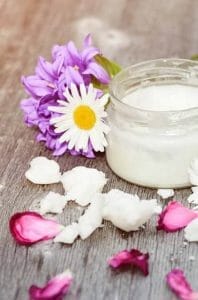 Coconut oil in a jar, next to flower petals
