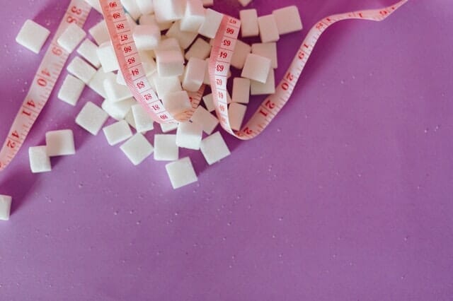  sugar cubes scattered around, a measuring cup next to it