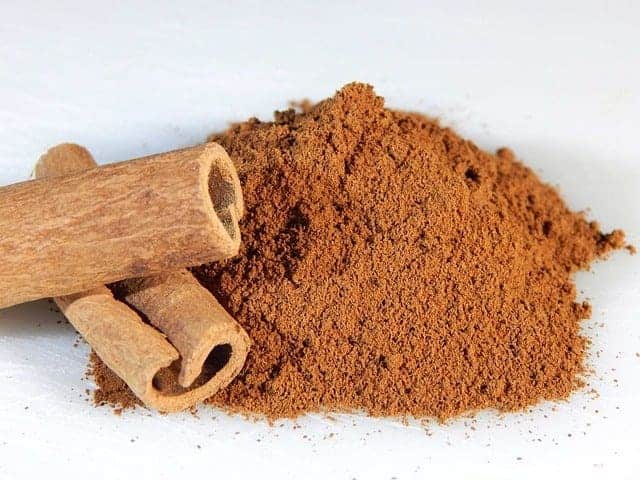 Ground cinnamon, next to cinnamon stick
