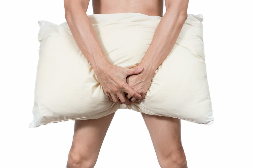  man covers crotch with pillow