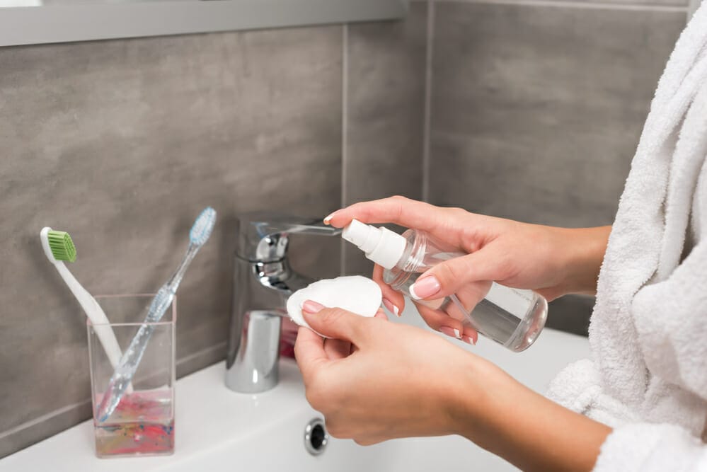 a woman holds a cotton swab and an acne product in her hand