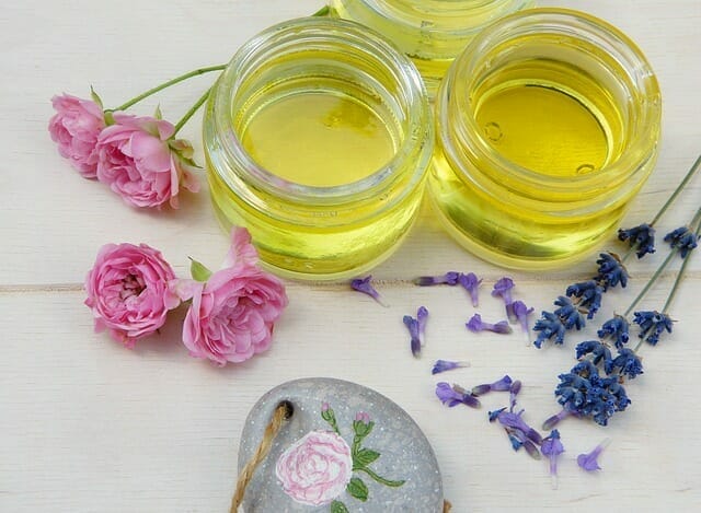  Cosmetic oils in jars, next to fresh flowers