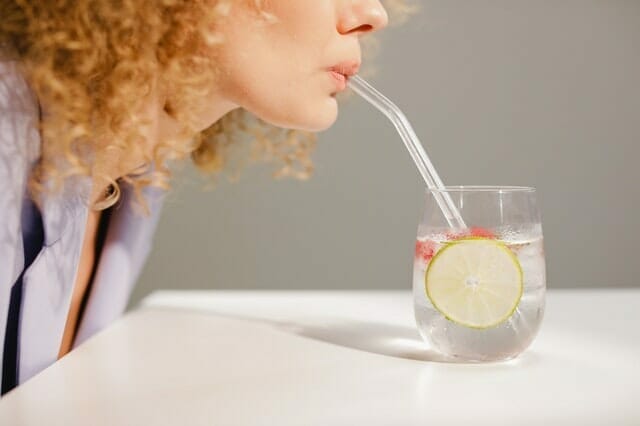  woman drinks water through a straw