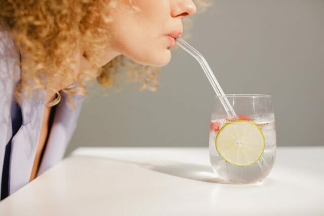 woman drinks water through a straw