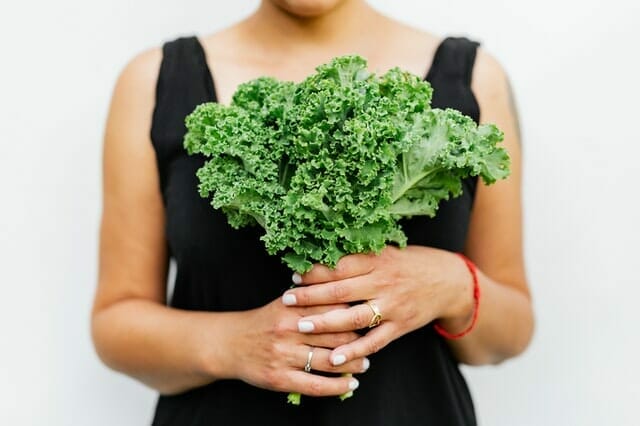 a woman holds kale in her hands