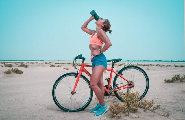 woman drinks water from a bottle after a bike ride