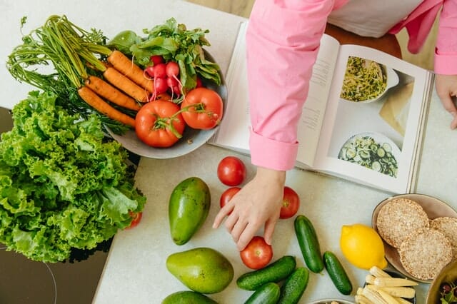 A cookbook and vegetables on the table