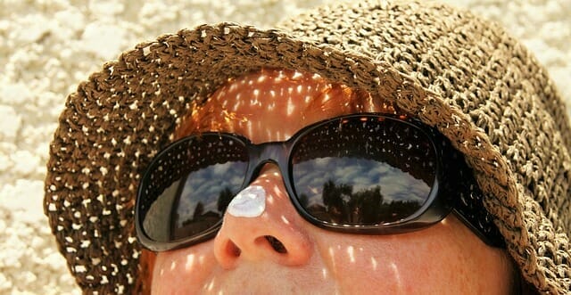 a woman's face in sunglasses and a hat