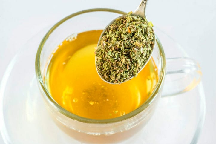A spoonful of purge herb, next to a glass of purge infusion