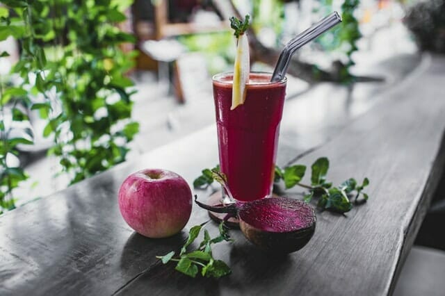 Beet juice in a glass, next to an apple and a beet