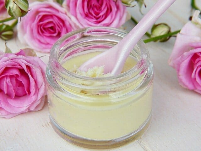 A jar with homemade face cream, next to it roses