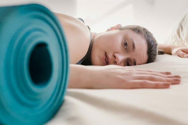  woman exhausted from training, next to exercise mat