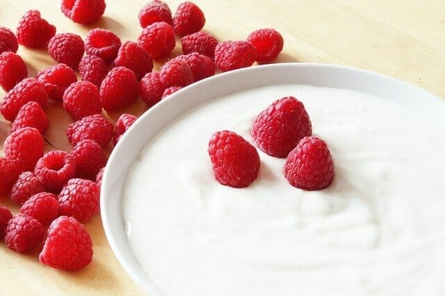 Yogurt in a bowl, next to raspberries