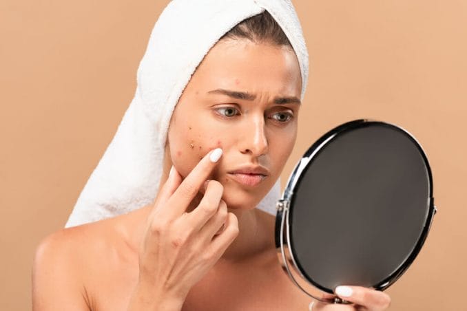  A woman watches the pimples on her face in the mirror