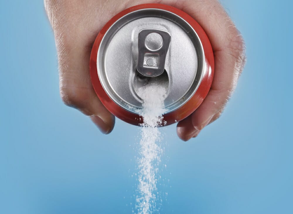 white sugar oozes out of a can of coca cola