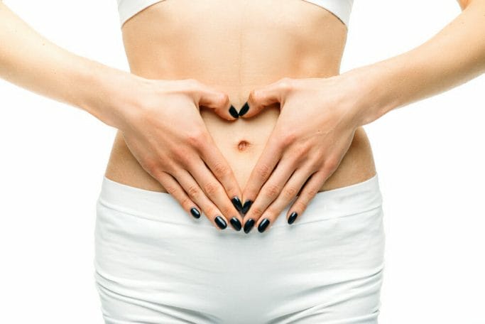 woman holds hands on her flat stomach