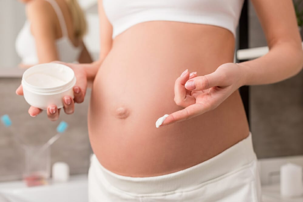 pregnant woman lubricates her belly with cream