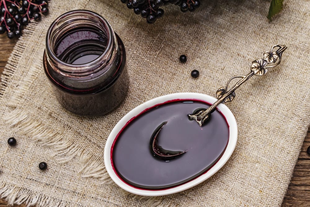  Elderberry juice in a jar and elderberry jam in a bowl.